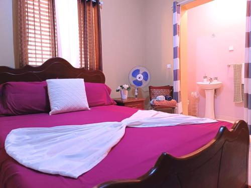 a bedroom with a large bed with pink and white sheets at Pensão Dona Fica in Tarrafal