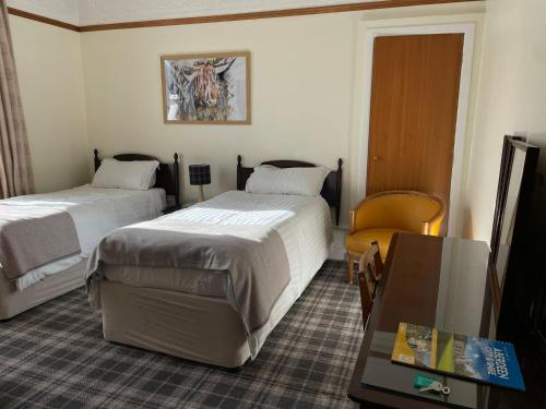 um quarto de hotel com duas camas e uma mesa em Bimini House em Aberdeen