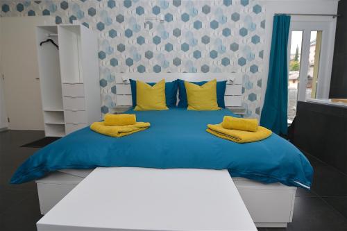 a bedroom with a blue bed with yellow pillows at Chambre d'hôte Valère in Sion