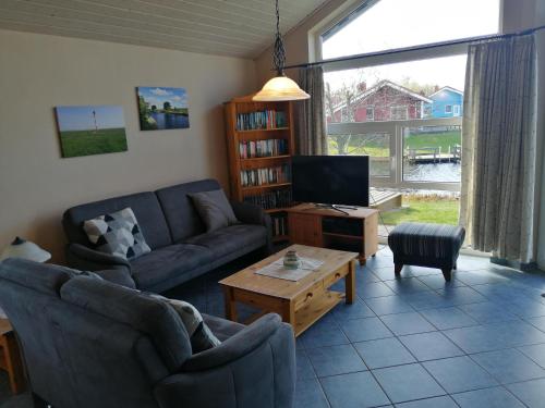 ein Wohnzimmer mit einem Sofa und einem TV in der Unterkunft Ferienhaus Kormoran in Otterndorf