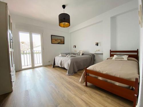 two beds in a bedroom with white walls and wooden floors at El ventanal del viajero in Baeza