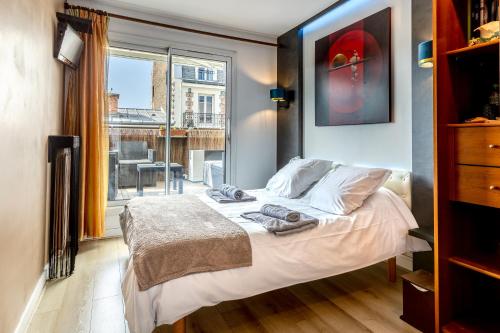 1 dormitorio con cama y ventana grande en Chambre d'Amis en París