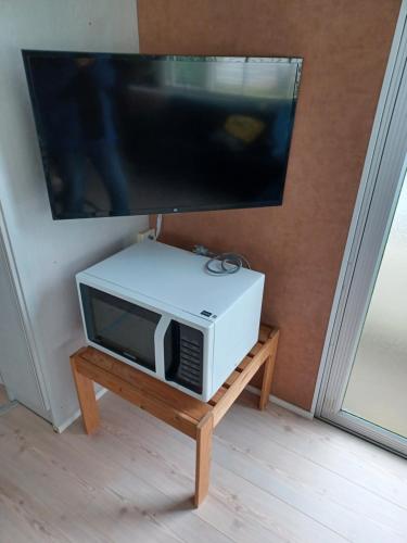 - un four micro-ondes assis sur une table sous une télévision dans l'établissement Stacaravan 426 met airco vakantiepark de Tien Heugten Schoonloo Drenthe, à Schoonloo