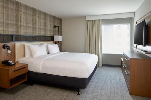 a hotel room with a bed and a flat screen tv at Residence Inn by Marriott San Francisco Airport Millbrae Station in Millbrae