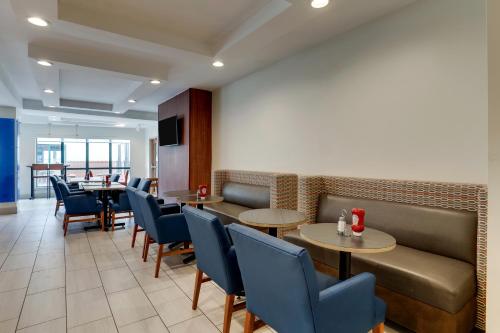a restaurant with tables and chairs and a couch at Holiday Inn Express Hotel & Suites Bryan-Montpelier by IHG in Holiday City