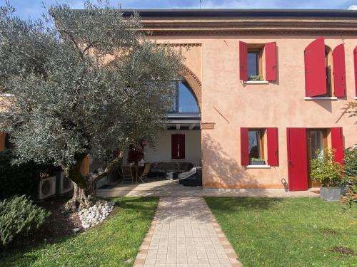 una casa con porte rosse e un albero nel cortile di Soranza Suite a Castelfranco Veneto