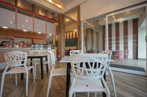 un restaurant avec des chaises blanches, une table et un comptoir dans l'établissement Residence 8, à Palembang