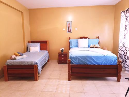 a bedroom with two beds with blue and white sheets at Pensão Dona Fica in Tarrafal