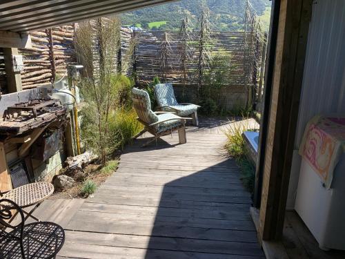 une passerelle en bois avec une chaise et un banc sur une terrasse couverte dans l'établissement Alpine Manuka View Cabin, à Kaikoura
