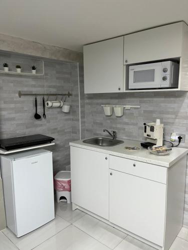 uma cozinha branca com um lavatório e um micro-ondas em Mortella House em Nápoles