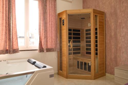 a bathroom with a wooden cabinet with a glass door at Napoli Central Lumina Suites in Naples