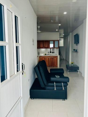 a living room with a black couch and a kitchen at TORRES DEL MESÓN LUXURY APARTA HOTEL Doradal in Doradal