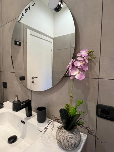 uma casa de banho com um espelho e um vaso com flores num lavatório em Le Terrazze di Chiara em Palermo