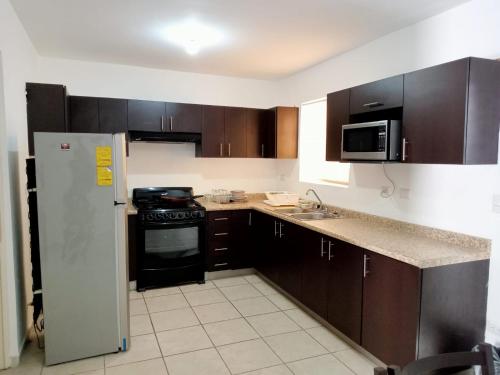 a kitchen with wooden cabinets and a refrigerator at AIRPORT APARTMENT MONTERREY 628 in Monterrey