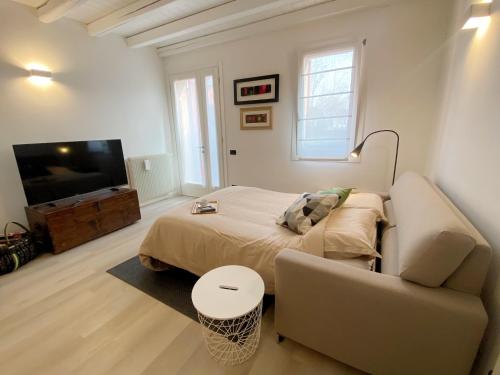 una camera con letto, divano e TV di Soranza Suite a Castelfranco Veneto