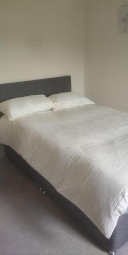 a bed with white sheets and pillows in a bedroom at Solihull Guest House 1 in Olton