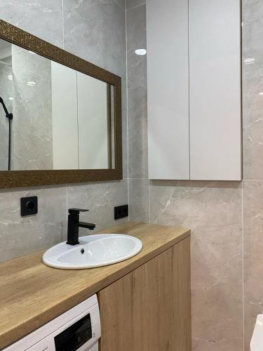 ein Bad mit einem Waschbecken und einem Spiegel in der Unterkunft Apartaments COSTA 2комн Нурлы жол-62 in Astana