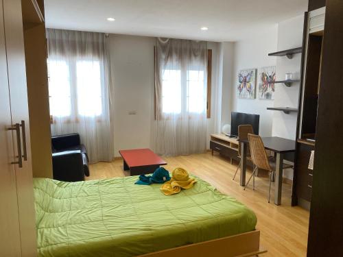 sypialnia z zielonym łóżkiem i biurkiem oraz pokój w obiekcie Estudio Céntrico D1 w mieście Oviedo
