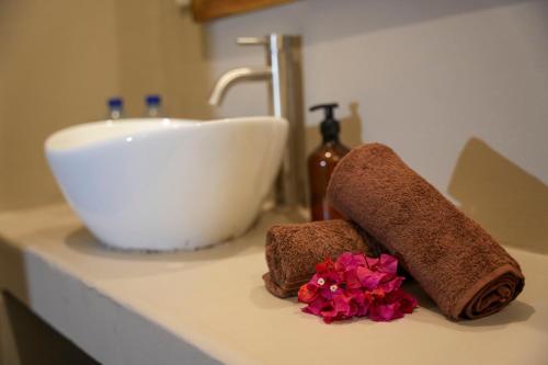 a bathroom counter with a sink and two towels and flowers at Kendwa Breeze Bungalows in Kendwa