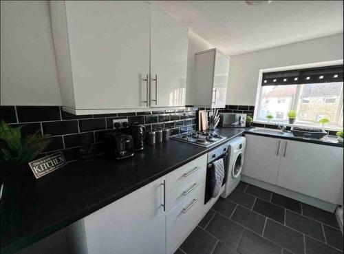 a kitchen with white cabinets and a black counter top at Spacious One-Bedroom in St. Helens in Burtonwood