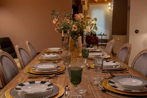 a wooden table with plates and glasses and a vase of flowers at Las Musas, Casa Rural in Hervás
