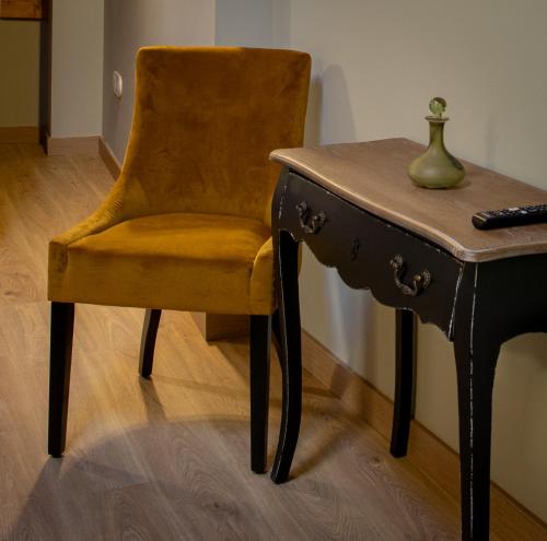 a chair next to a desk and a table with a vase at Las Musas, Casa Rural in Hervás