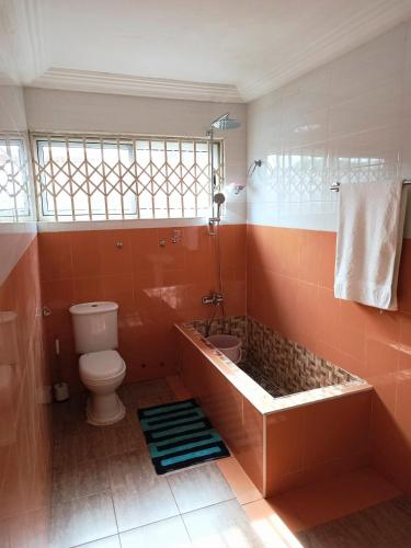 a bathroom with a tub and a toilet and a window at jetfastventure in Accra