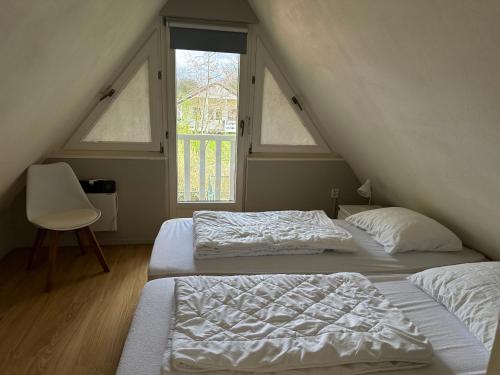 2 camas en una habitación con 2 ventanas en Vakantiehuis Sofie Lauwersmeer met sauna en Anjum