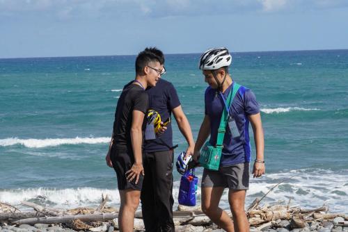 two men standing on the beach near the ocean at On My Way Dulan in Donghe