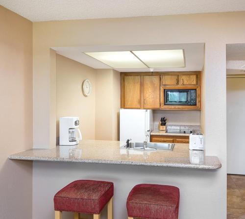 uma cozinha com um balcão com dois bancos vermelhos em WorldMark Palm Springs - Plaza Resort and Spa em Palm Springs