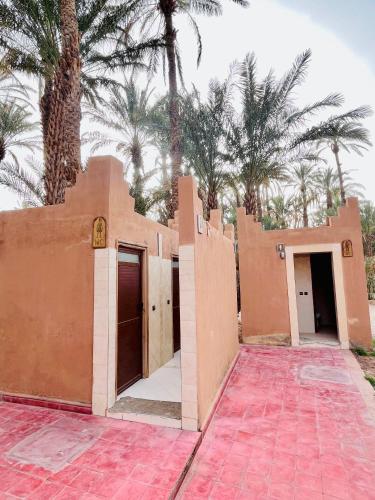 a building with palm trees in the background at Camping auberge palmeraie d'amezrou in Zagora