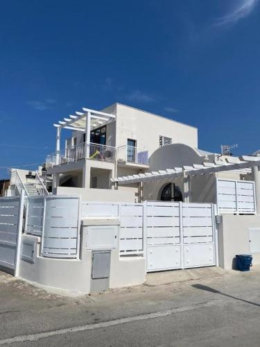 una casa blanca con puertas blancas y una valla en Donna Cuncetta Soppalco Monte di Procida, en Monte di Procida