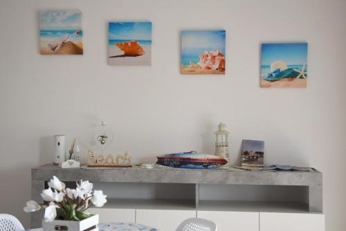 une étagère dans une pièce avec quatre photos sur le mur dans l'établissement Appartamento Lago Playa, à Desenzano del Garda