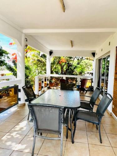 een eetkamer met een tafel en stoelen op een veranda bij Villa baobab in Ramena