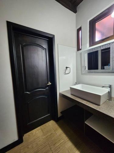 a bathroom with a black door and a sink at Apartamento 1 Premiere de Occidente in Quetzaltenango
