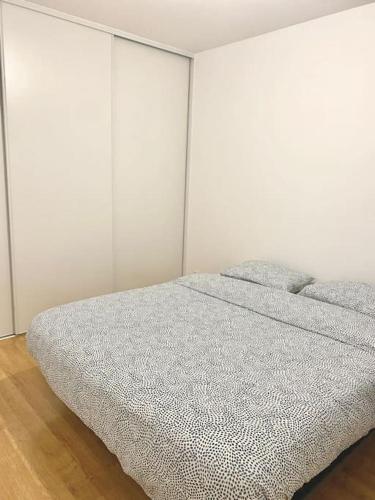 - une chambre blanche avec un lit et une couverture grise dans l'établissement Charmant T2 calme proche frontière Suisse, à Saint-Julien-en-Genevois