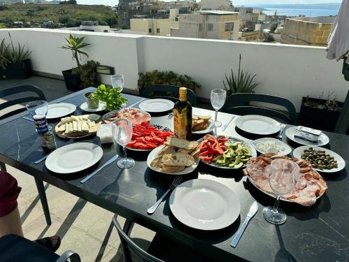 a table with plates of food and glasses of wine at Millennium Penthouse with private Hot Tub Gozo in Għajnsielem