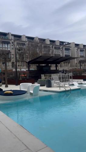 a swimming pool with chairs and a building in the background at Atlanta Beltline Luxury Suite in Atlanta