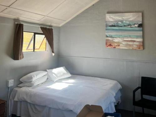 a bedroom with a white bed with a window at Tin Can Glamping Caravan in Underberg
