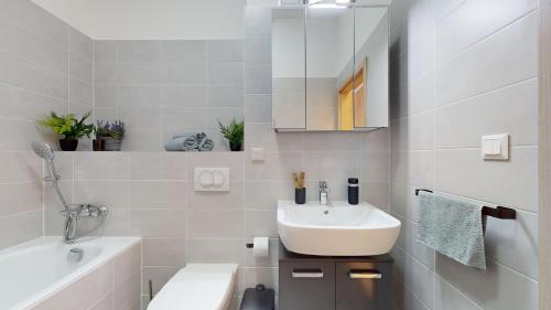 La salle de bains blanche est pourvue d'un lavabo et d'une baignoire. dans l'établissement 3unity Apartman Kamence, à Kysucké Nové Mesto