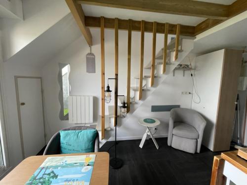 a room with a staircase and a table and chairs at APPARTEMENT VUE PORT CROUESTY in Arzon