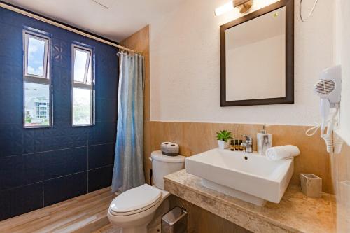 a bathroom with a sink and a toilet and a mirror at Via Tendenza Condos in Playa del Carmen