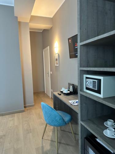 a room with a blue chair and a desk with a microwave at Sunset Guest House in Reggio Calabria