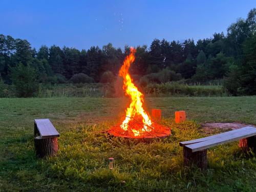 a fire in the middle of a field with two benches at 3pokoje - Domek lub Pokój pod lasem na odludziu, jacuzzi, sauna, kominek, Roztocze in Susiec