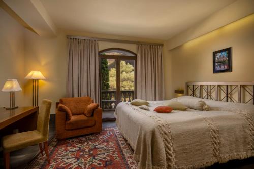 a bedroom with a bed and a chair and a window at Tufenkian Avan Dzoraget Hotel in Dzoraget