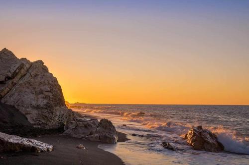 - une plage avec des rochers et l'océan au coucher du soleil dans l'établissement Appartement T2 avec terrasse et Vue mer à Béjaïa proche plage, à Béjaïa