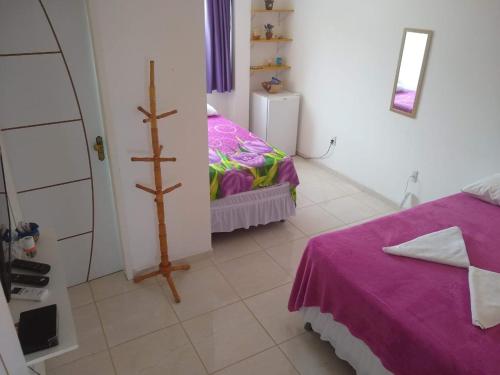 馬拉戈日的住宿－Pousada Lá na Praia Maragogi，一间带紫色床的卧室和一间小型客房。