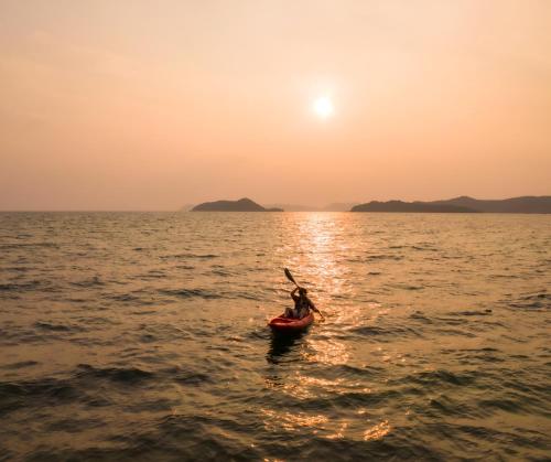 a person in a kayak in the ocean at sunset at Ban Chang Pet-friendly Hotel by SCN in Ban Chang