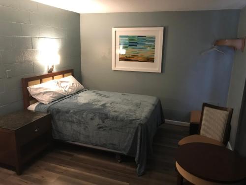 a small bedroom with a bed and a table at Lamplighter Motel in Longmont