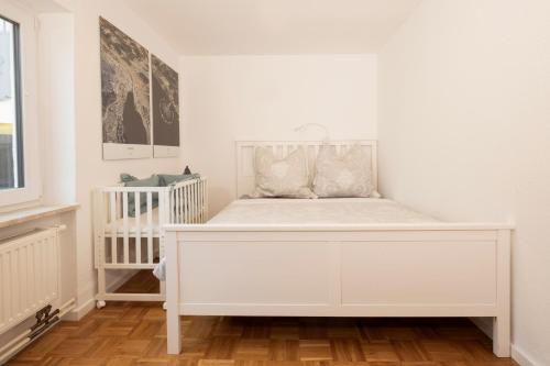 een wit bed in een kamer met een wieg bij Alpenblick Familienparadies in der Bodenseeregion in Ravensburg
